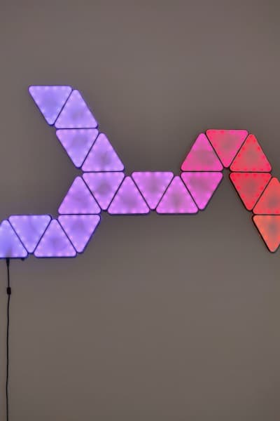 Image of triangular LED panels on wall, changes color when hovering cursor.